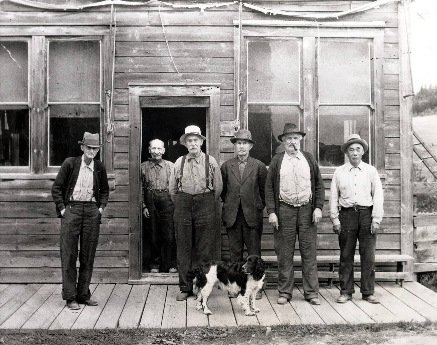 L-R: Billie Allen, Little Gus Gustafson, Henry Holzman, Martin Hickman, Fred Franklin, Charlie Wong Gee standing in front of Old Blue Front Saloon. Elk City, Idaho.